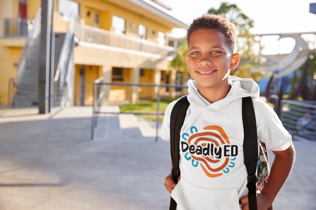 A young schoolboy wearing a backpack and white jumper with a deadly ed logo.