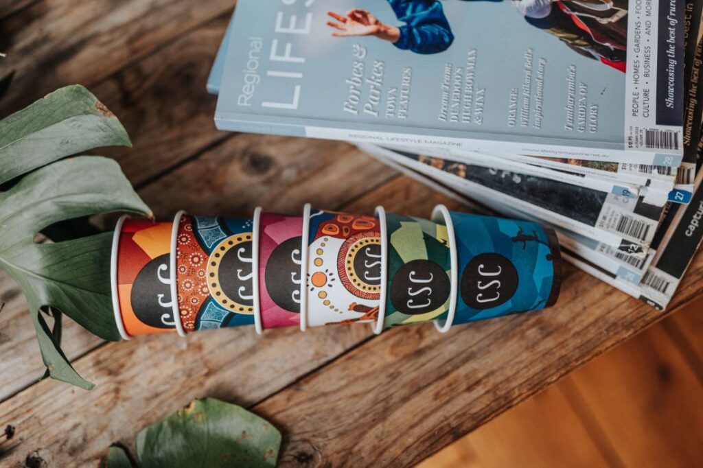 Stacked cups on a table with magazines next to it.