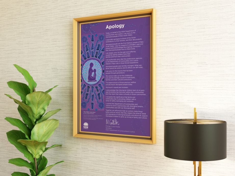 A large framed artwork hanging on a wall. The artwork is purple with two people in the middle and the caption 'The Children Came Home'.