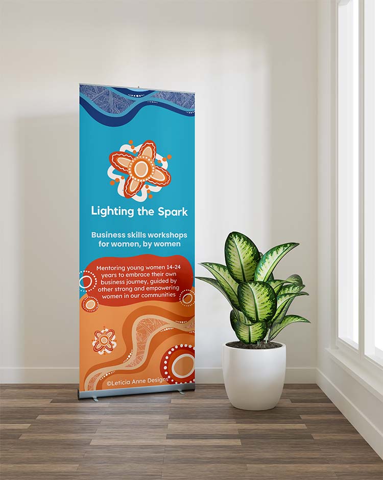 A pull up banner with information about Lighting the Spark. There is a tall plant next to it.